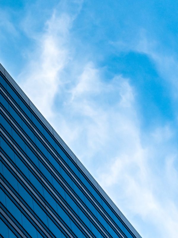 A low angle shot of tall glass buildings under a cloudy blue sky